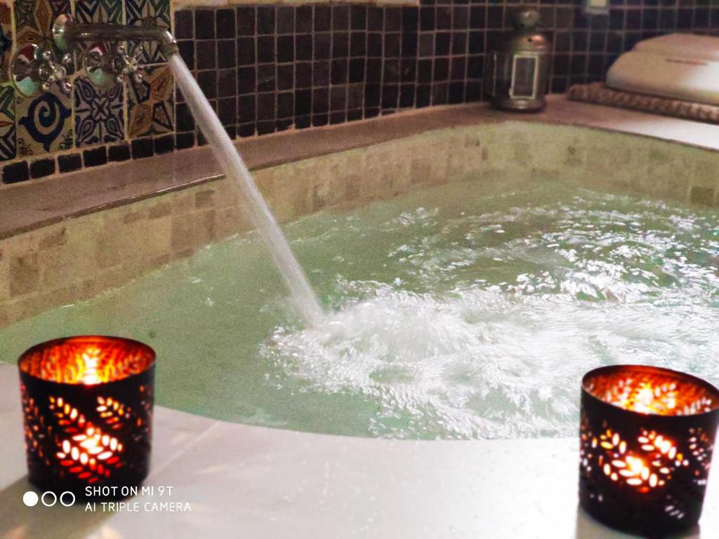 Al-Axara Home Spa في Cubas: حوض استحمام ساخن مع نافورة مياه مع شمعتين