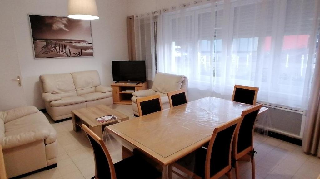 een woonkamer met een tafel en stoelen en een televisie bij Le Cottage Malouin in Duinkerke