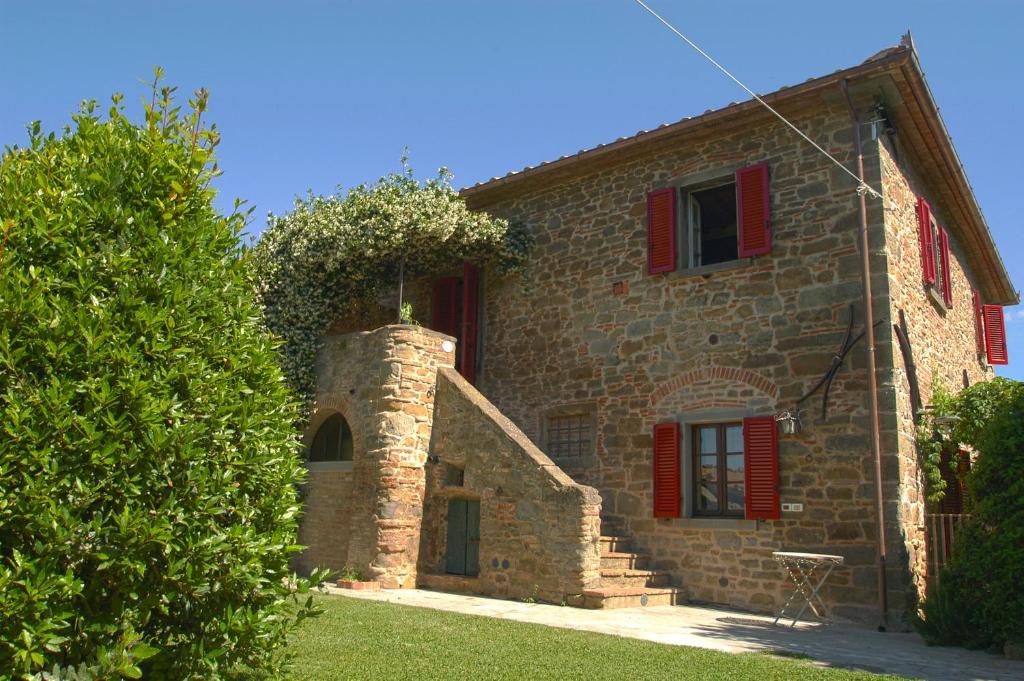 a stone house with red shutters on the side of it at Holiday apartments La Bozza and Il Bozzino in Cortona