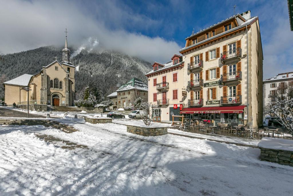 uma cidade na neve com um edifício e uma igreja em Hotel Le Chamonix em Chamonix-Mont-Blanc