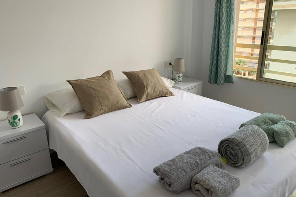 a bedroom with a white bed with towels on it at Apartamento Frente al mar, RECIEN RENOVADO, 1 hab 1 baño in El Campello