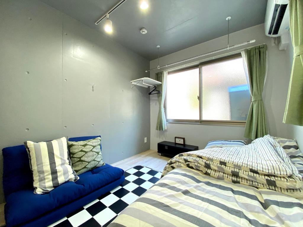 a bedroom with two beds and a blue couch at Belle harmonie togoshi101 in Tokyo