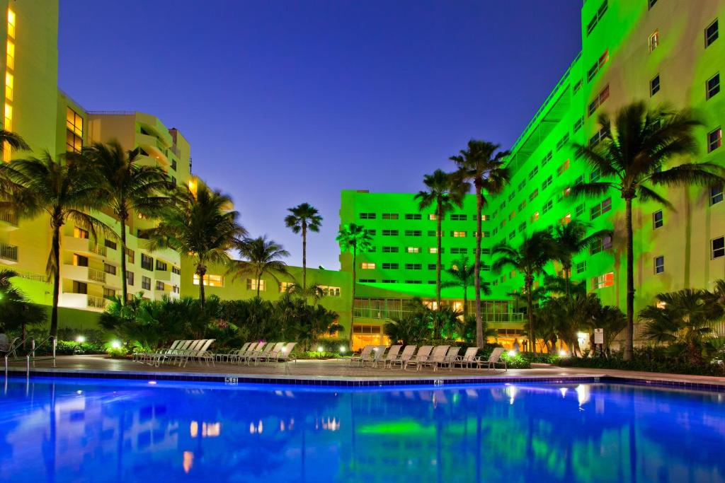 a swimming pool in front of a building with palm trees at Holiday Inn Miami Beach-Oceanfront by IHG in Miami Beach