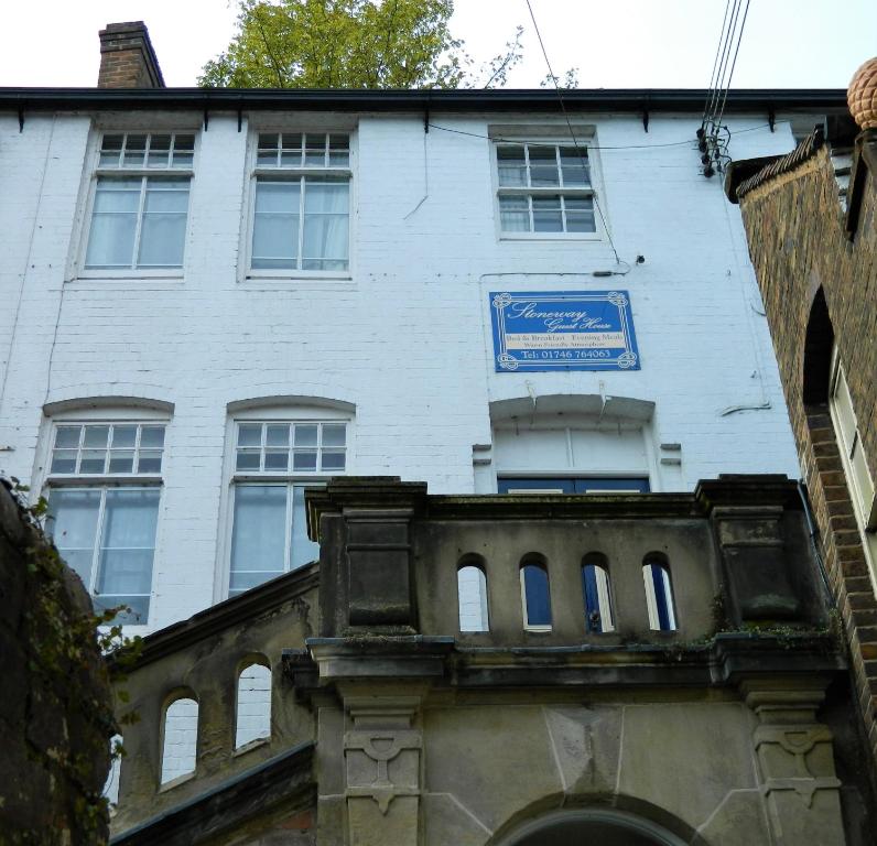 a white building with a blue sign on it at Stoneway Guest House in Bridgnorth
