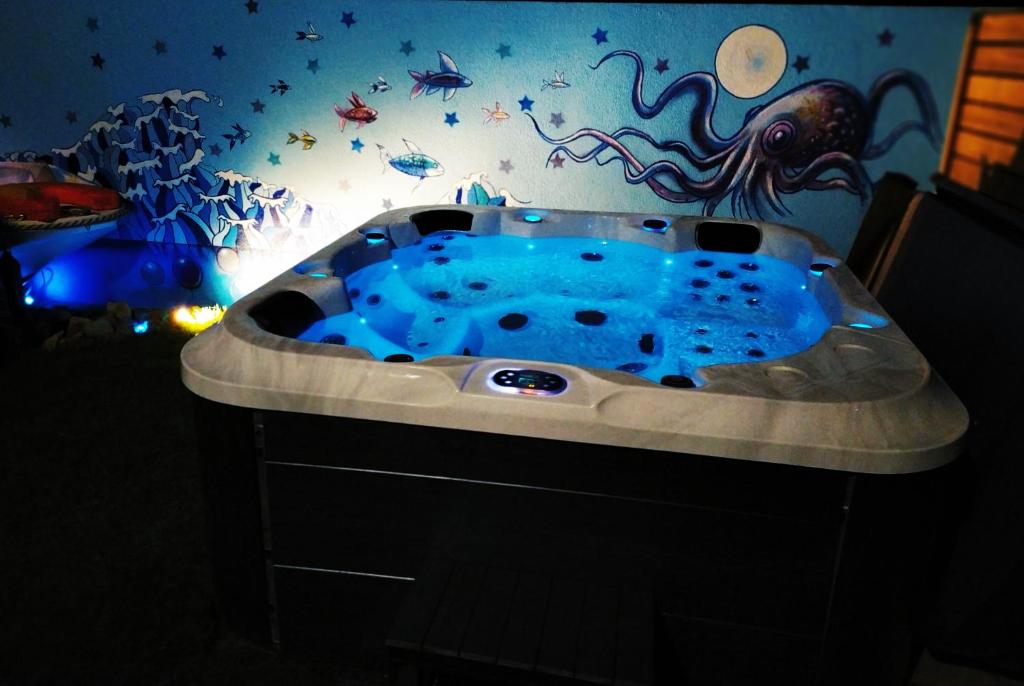 La salle de bains est pourvue d'une baignoire bleue avec un mur en pieuvre. dans l'établissement LOGEMENT ATYPIQUE BIEN ETRE AU CŒUR DE LA NATURE, à Quimper