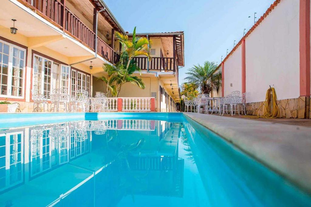 a swimming pool in a hotel with chairs and a building at Pousada Coração Inconfidente in Tiradentes