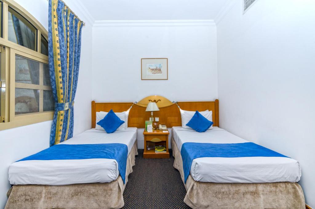 Habitación de hotel con 2 camas y almohadas azules en Zain International Hotel, en Dubái