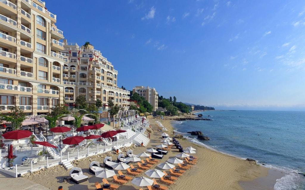 a beach with umbrellas and chairs and a building at La Mer Penthouse in Varna City