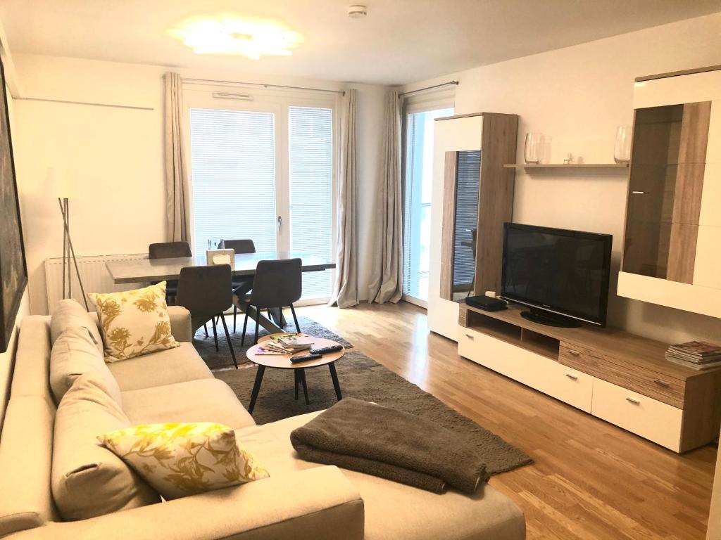 a living room with a couch and a flat screen tv at Amazing Austria Center Apartment near UNO City in Vienna