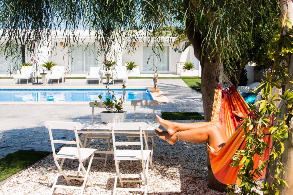a woman sitting in a hammock by a pool at Finca Pura, Clothing Optional Guestrooms in Elche