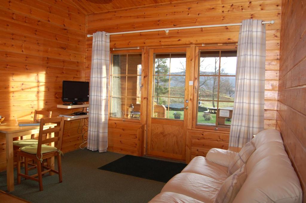 een woonkamer met een bank en een bureau bij Cosy & compact Rowan Lodge no2 in Killin