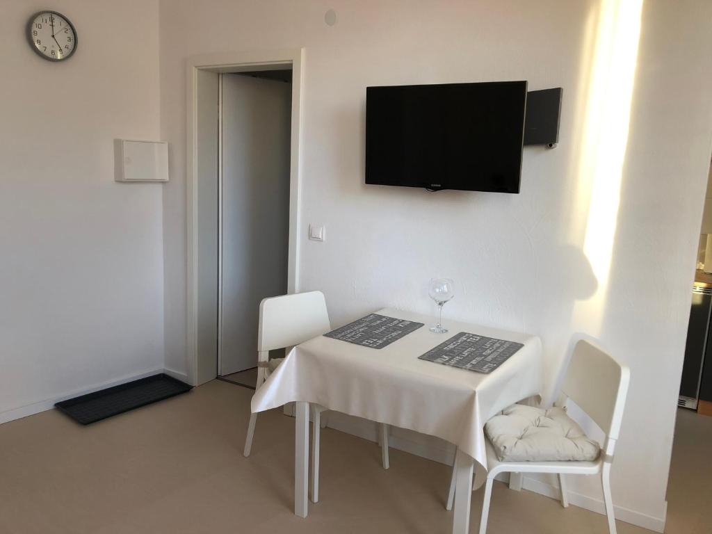 ノルトハイムにあるApartment in OG Schaupenstielの白いテーブル(椅子2脚付)、壁掛けテレビ