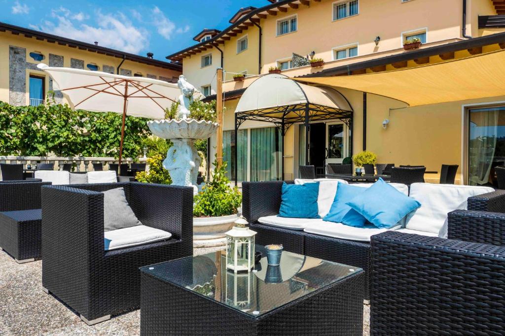 a patio with wicker furniture and a fountain with blue pillows at Hotel Borgo dei Poeti Romantik Wellness & SPA in Manerba del Garda