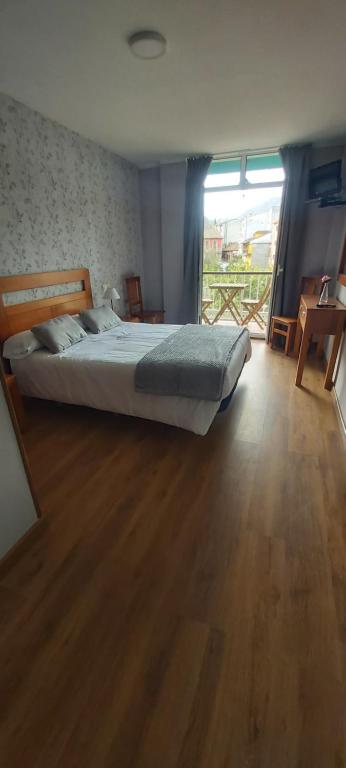 um quarto com uma cama e piso em madeira em Hotel Águila Real em Cangas de Onís