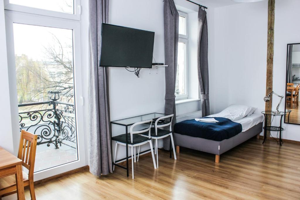 a bedroom with a bed and a table and a balcony at Apartamenty Babina in Kalisz