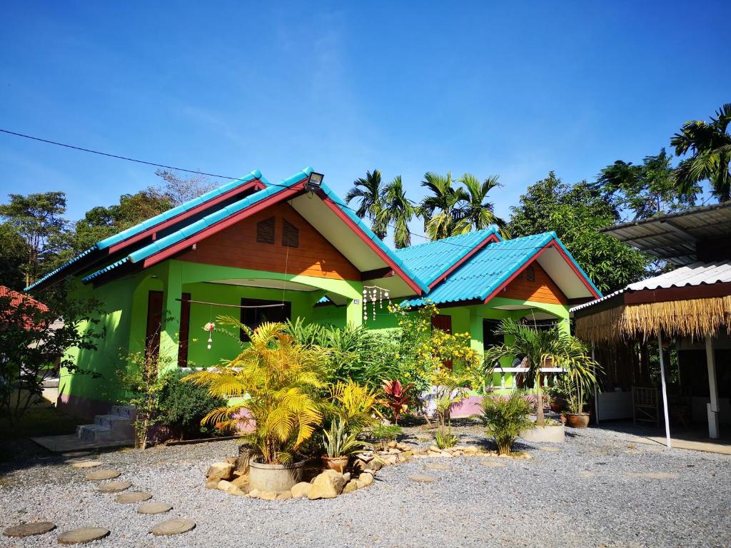 uma casa verde com um telhado azul e algumas plantas em Papaya Cottage Koh Chang em Ko Chang