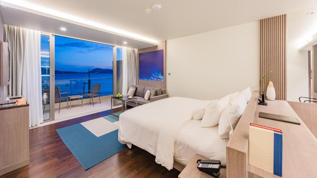 a bedroom with a bed and a view of the ocean at Oceanfront Beach Resort - SHA Extra Plus in Patong Beach