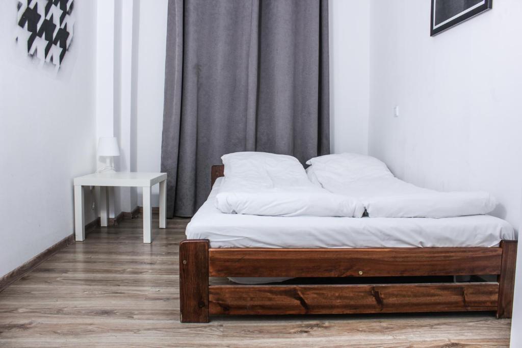 a bedroom with a bed with white sheets and a table at Baba Hostel in Kalisz