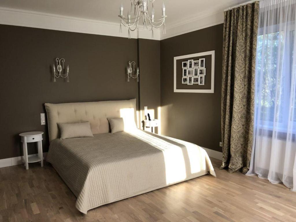 a bedroom with a large bed and a chandelier at PRIVATE ELITE VILLA IN JURMALA in Jūrmala