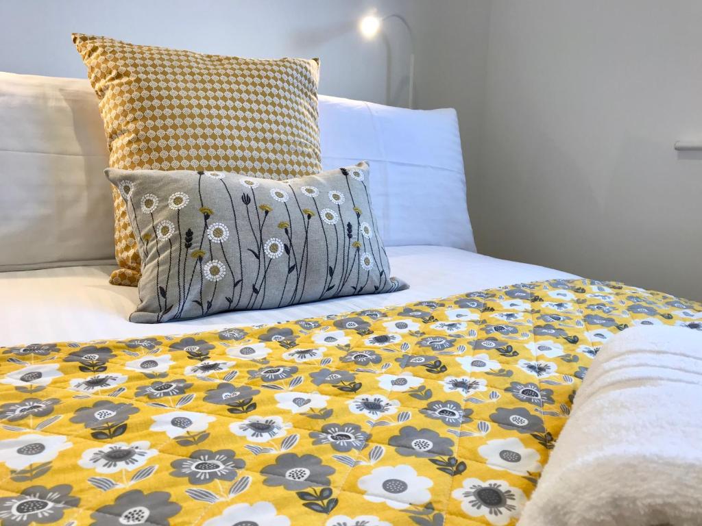een bed met een gele en witte deken en 2 kussens bij Charming 3 Bedroom House garden & parking - next to CS Lewis Nature Reserve in Oxford