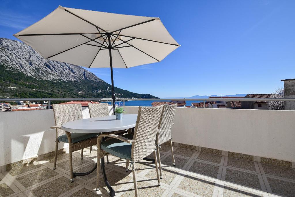 a table and chairs with an umbrella on a balcony at Apartman Luka in Igrane