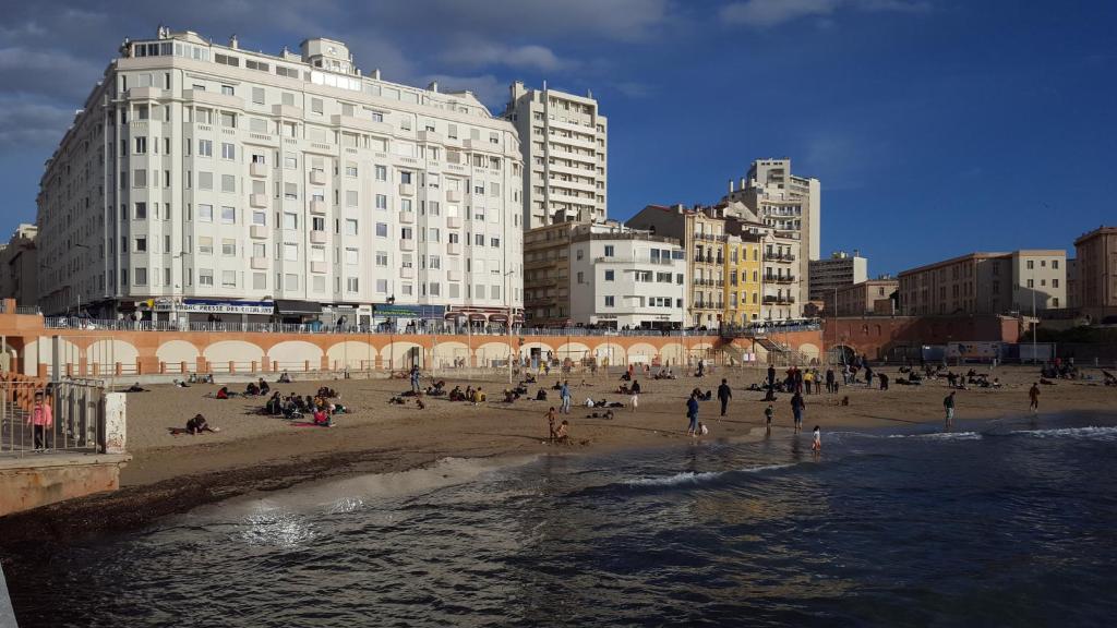 un groupe de personnes sur une plage avec des bâtiments dans l'établissement Le LAZARET, à Marseille