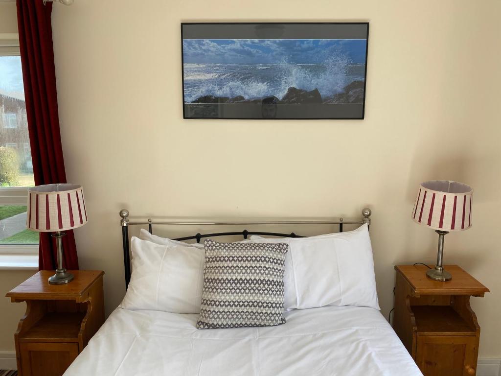 1 dormitorio con 1 cama con 2 lámparas y una foto en la pared en Mary Green Walk, en Canterbury