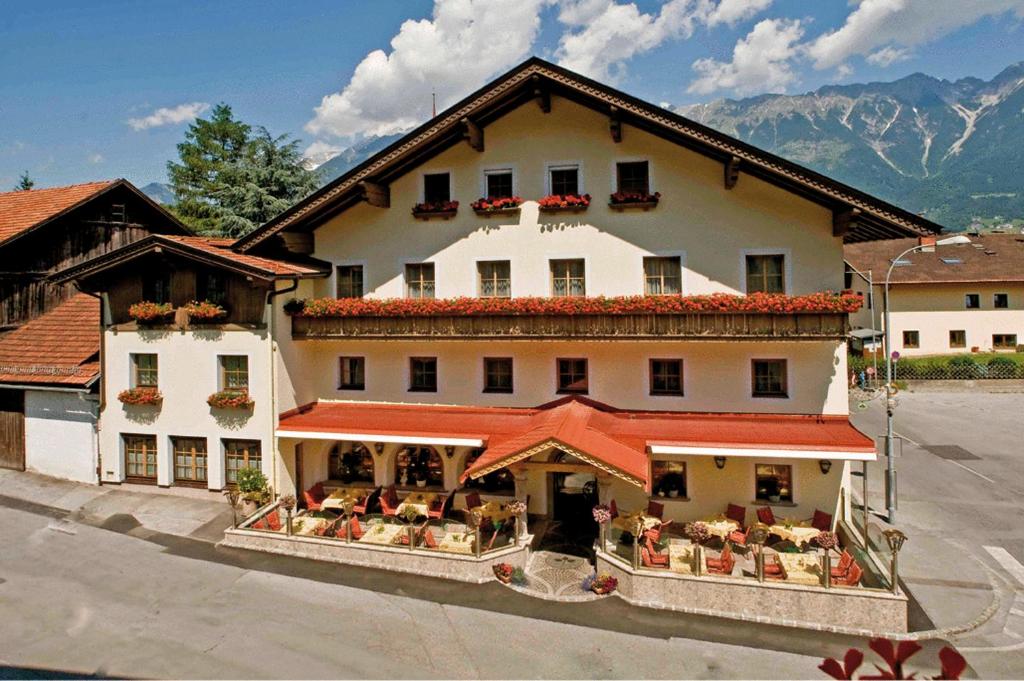 un grand bâtiment avec des tables et des chaises devant lui dans l'établissement Hotel Bierwirt, à Innsbruck