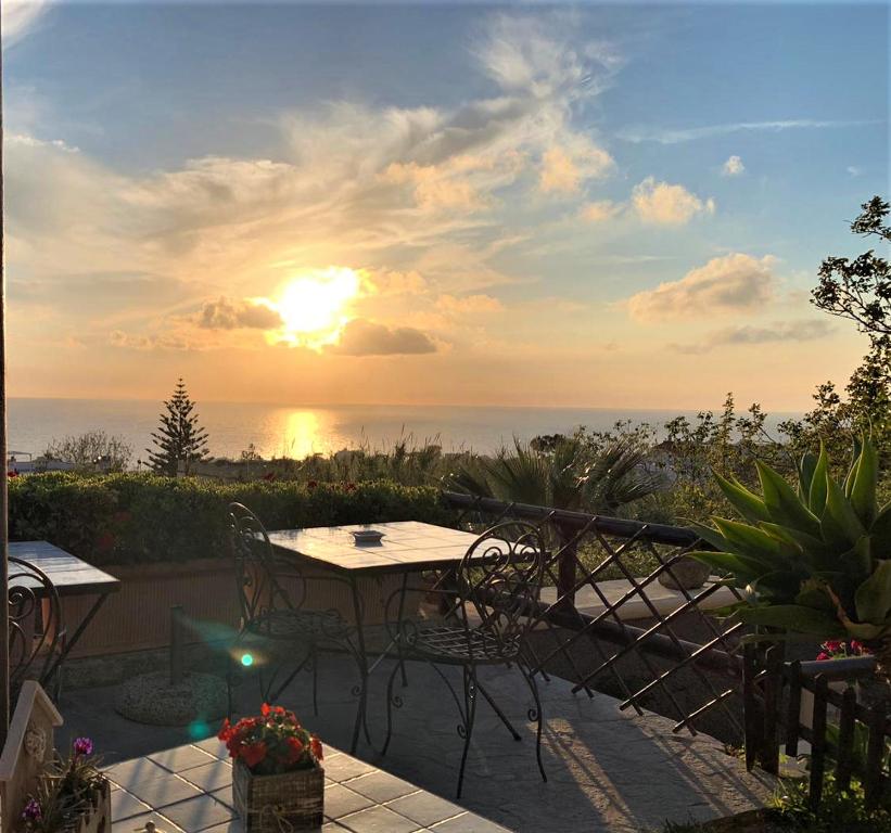 a table and chairs on a patio with the sunset at La Terrazzina sul tramonto in Ischia