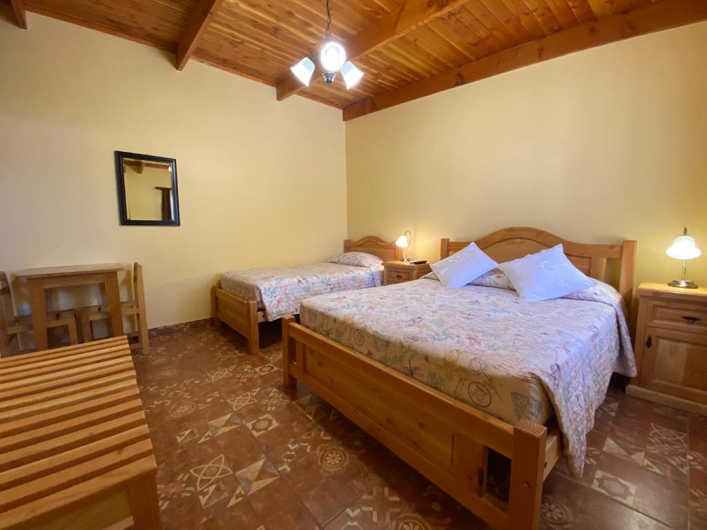 1 dormitorio con 2 camas, 2 mesas y espejo en Las Cornizas de Catarpe, en San Pedro de Atacama