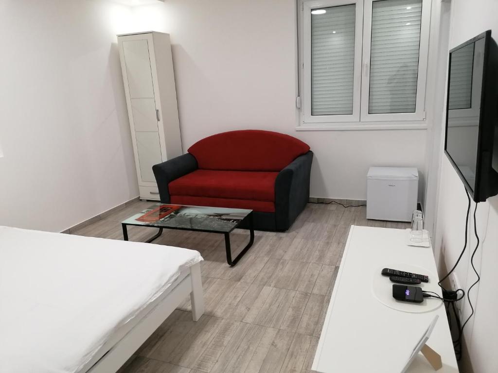 a living room with a red chair and a table at Airport view Apartment in Belgrade