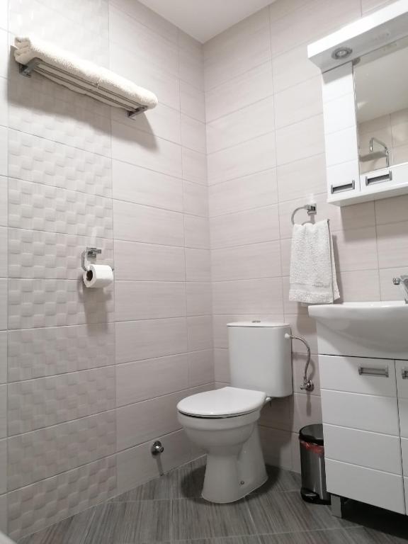 a white bathroom with a toilet and a sink at Airport view Apartment in Belgrade