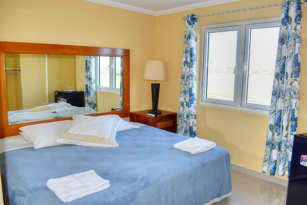 a bedroom with a blue bed and a mirror at Palm Beach Retreat in Palm-Eagle Beach