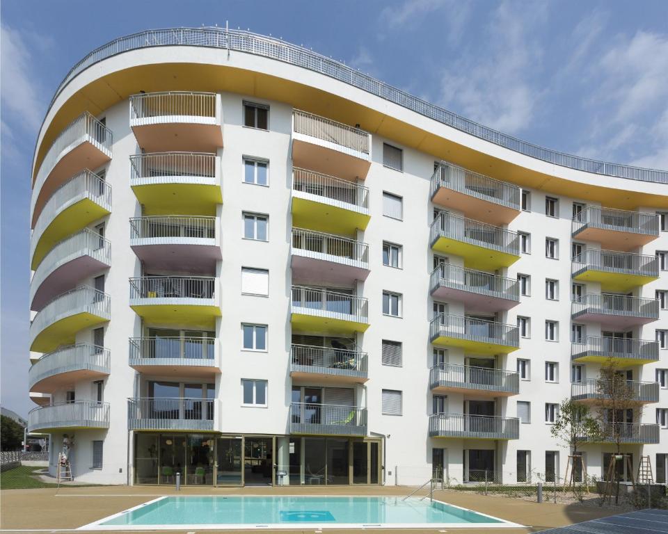 ein Apartmenthaus mit einem Pool davor in der Unterkunft IG City Apartments Danube Lodge in Wien