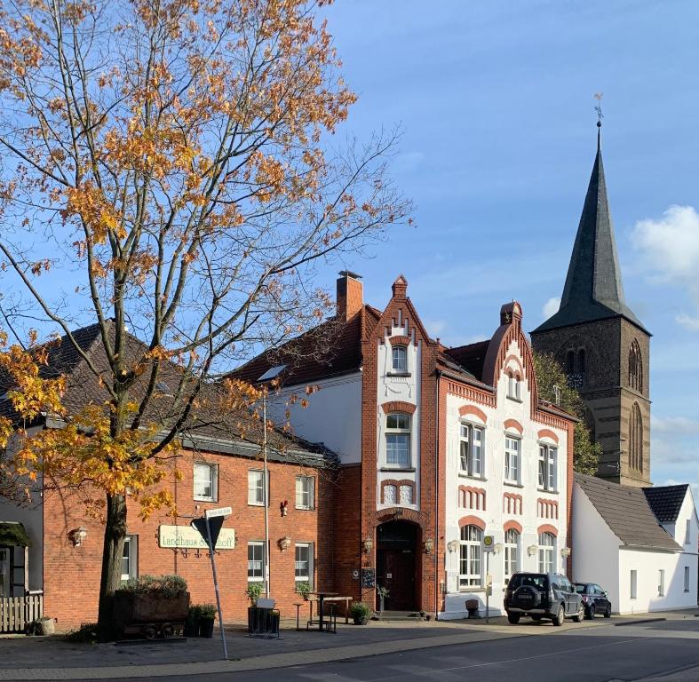 a large brick building with a steeple on a street at Hotel Landhaus Steinhoff in Rheinberg