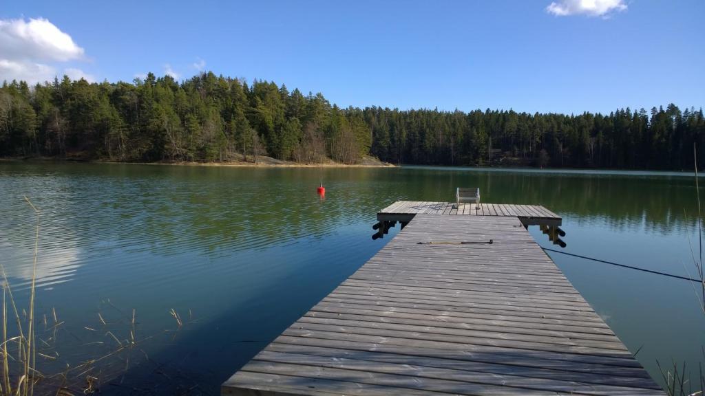 a wooden dock on a lake with trees in the background at Päiväkulma in Naantali