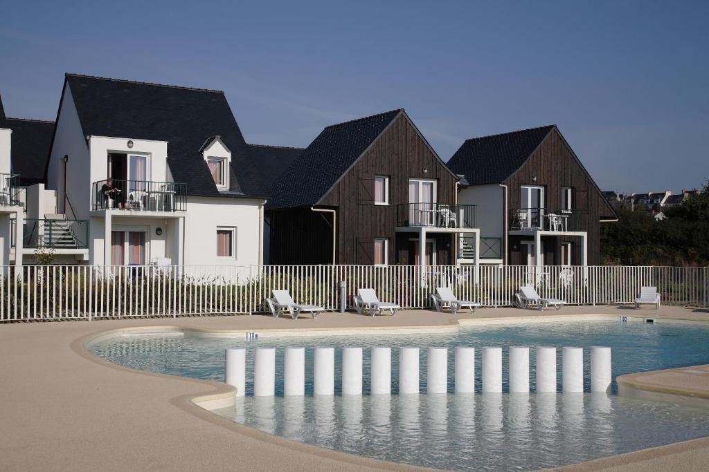 a swimming pool in front of some houses at Résidence Néméa Les Roches in Saint-Pol-de-Léon