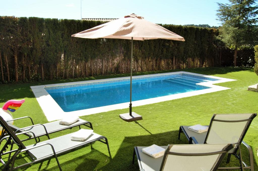 a pool with chairs and an umbrella and a pool at Villa Babette in Vidreres