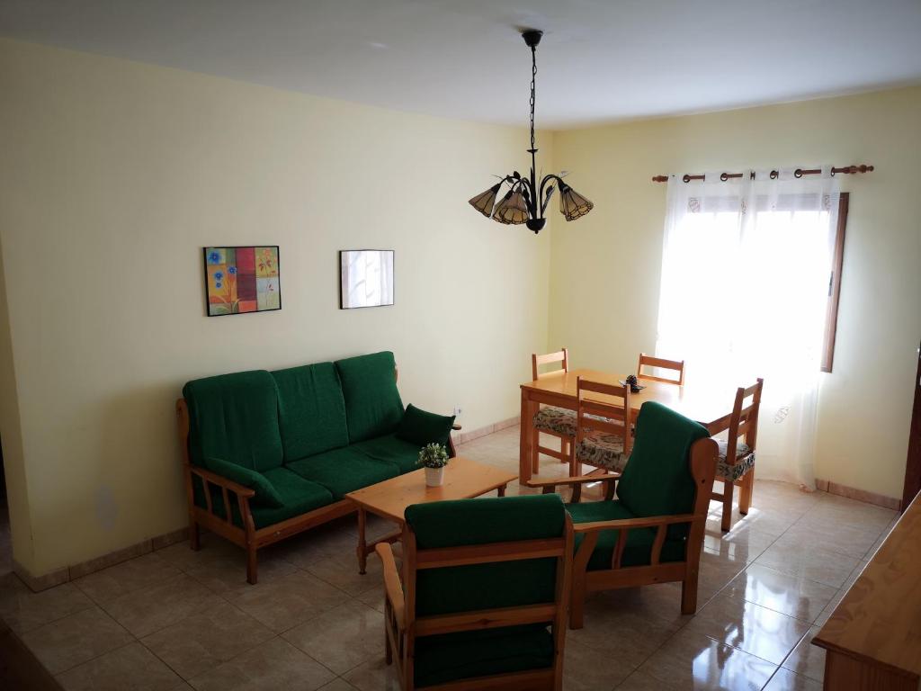 sala de estar con sofá verde y sillas en La Casita de Ana, en San Sebastián de la Gomera