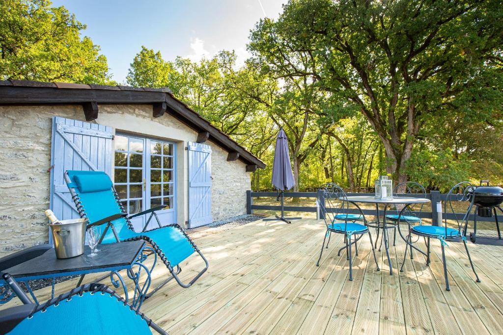 een terras met stoelen en een tafel en een grill bij La Terrasse - A Peaceful Place in the Forest in Concots