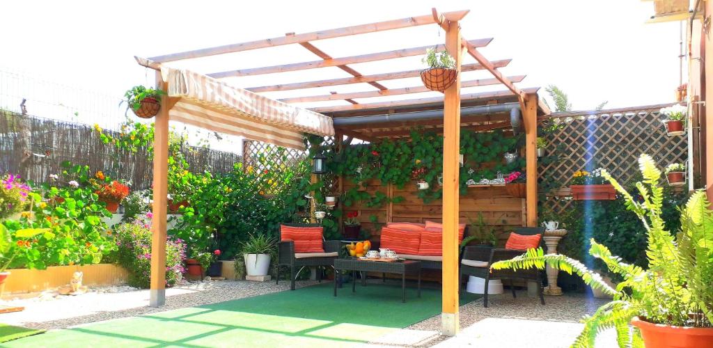 a wooden pergola with a table and chairs in a garden at Alojamiento El Altet Playa in El Alted
