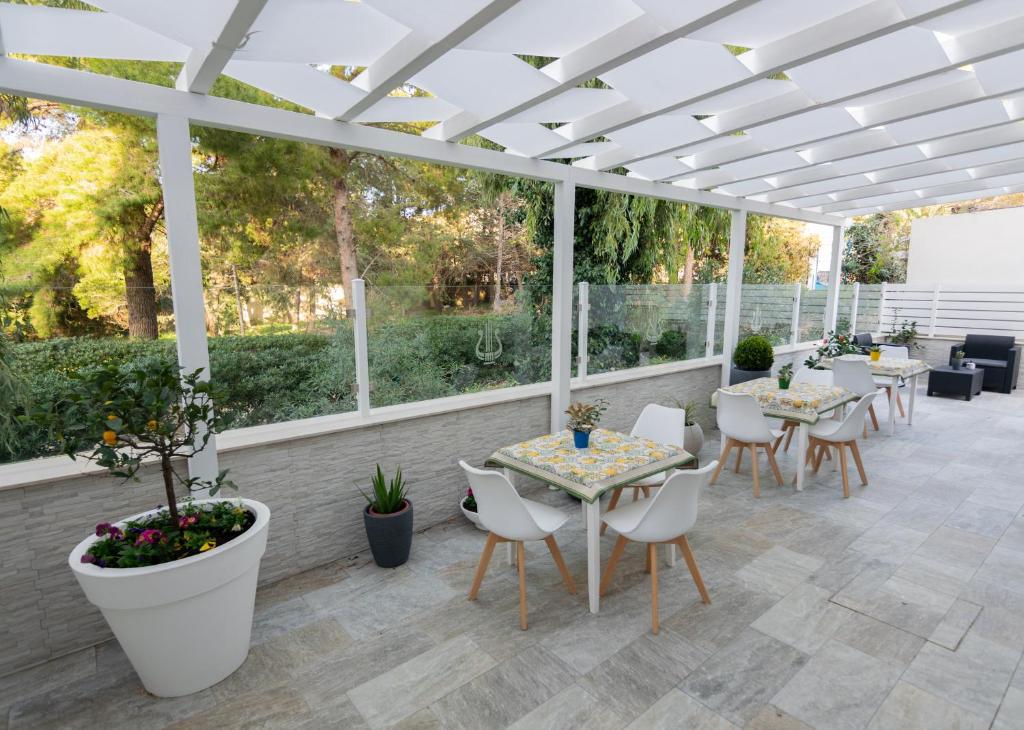 un patio con tavoli e sedie sotto un pergolato bianco di Apollo Bed & Breakfast a Agrigento
