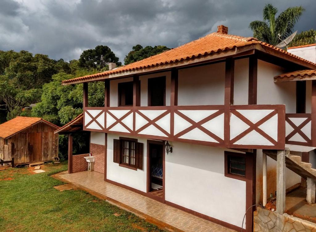 une maison blanche avec un toit rouge dans l'établissement Pousada Caminho das Araucárias, à Camanducaia