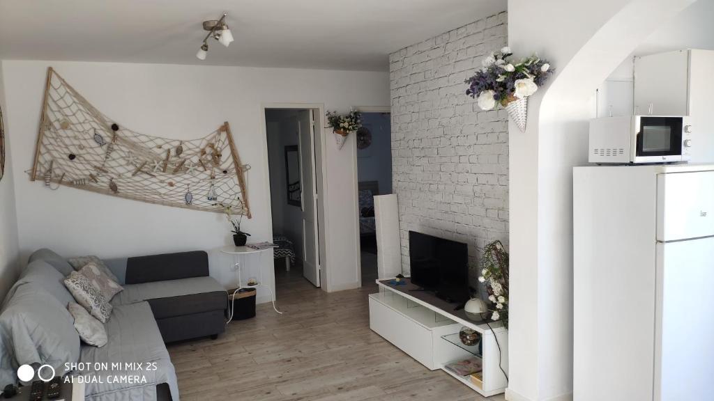 een woonkamer met een bank en een bakstenen muur bij Appartamento Delia in Caleta De Fuste