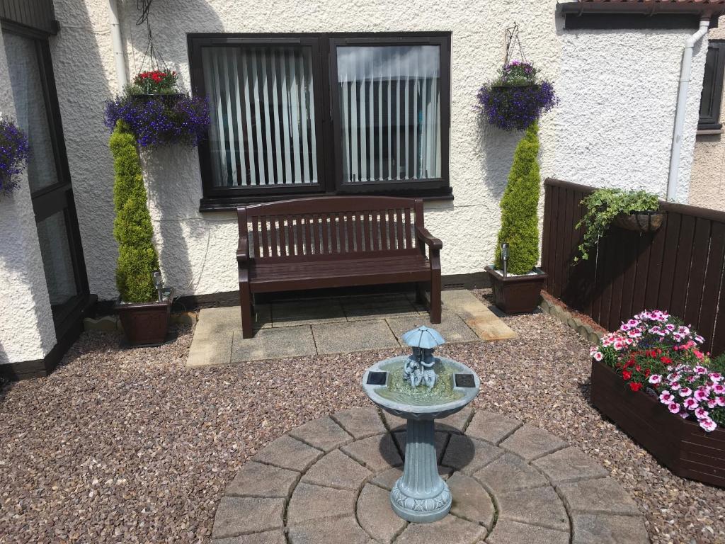 a patio with a bench and flowers in front of a house at Highland Home in Fort William