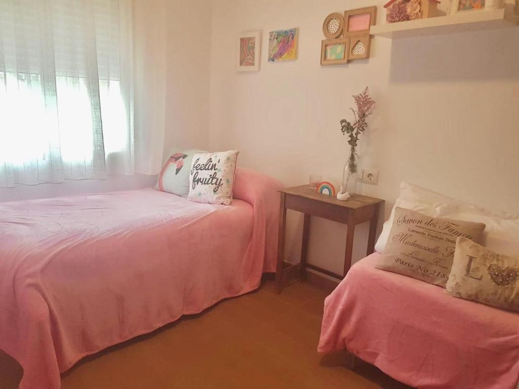 a room with two beds with pink sheets and a table at Casa con piscina de agua salada Villa Pepucho 1 in Córdoba
