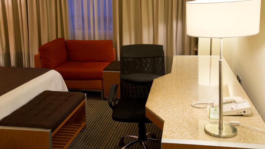 A large corner desk faces a curtained window beside a sofa and office chair.