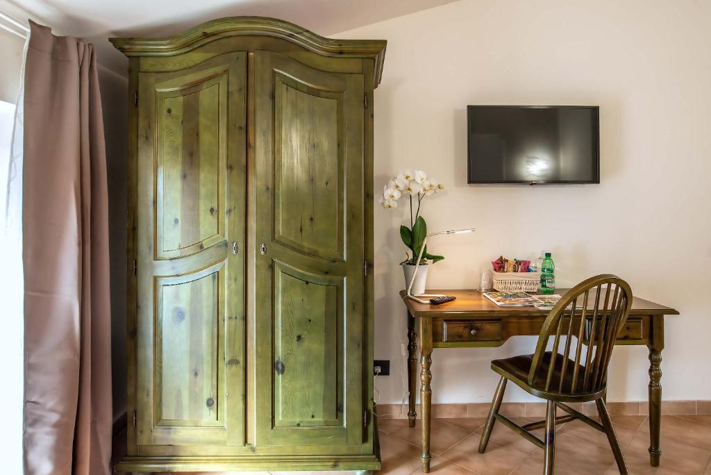 a green wooden cabinet next to a table with a chair at Plaza Rooms Ciampino in Ciampino