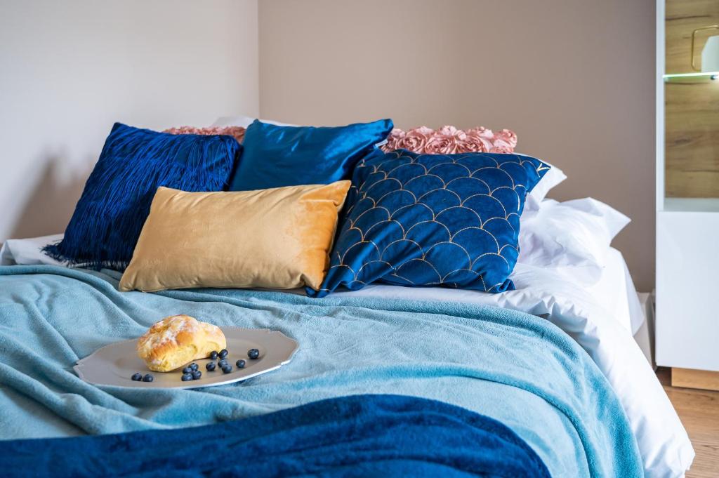 ein Teller mit Essen auf einem Bett mit blauen Kissen in der Unterkunft P&O Apartments Rondo Radosława in Warschau