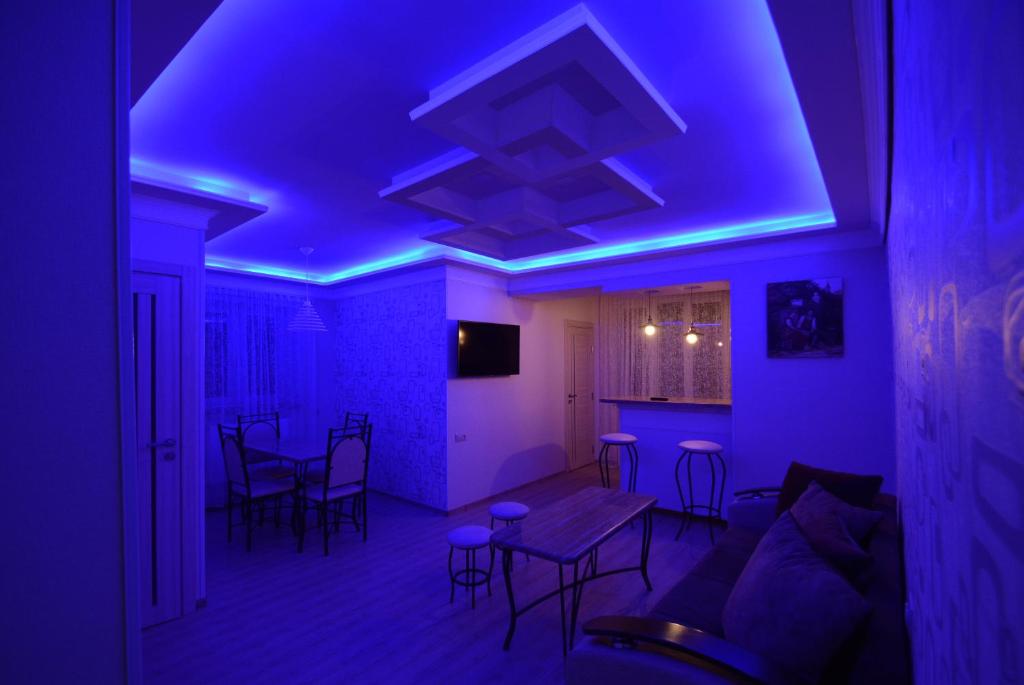 un soggiorno con luci viola, tavolo e sedie di Apartment a Sevan